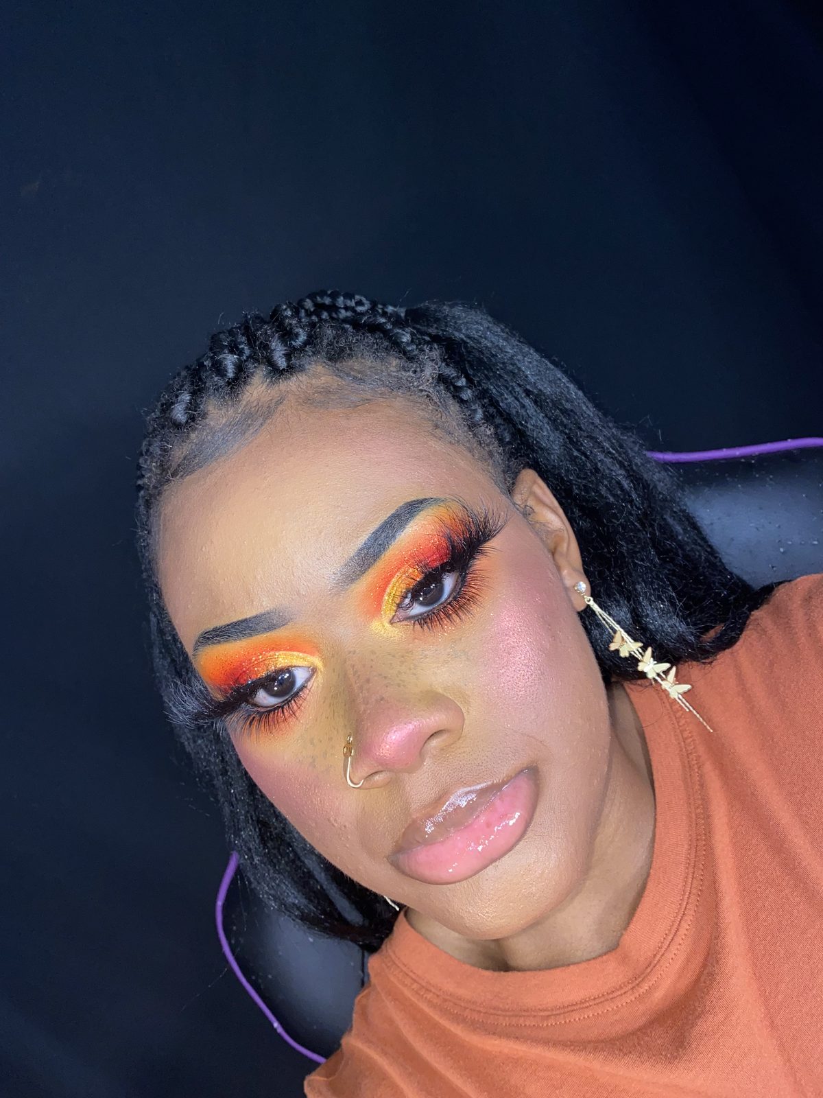 Aliyah wearing a fiery red, orange and gold glitter eye look with butterfly drop earrings